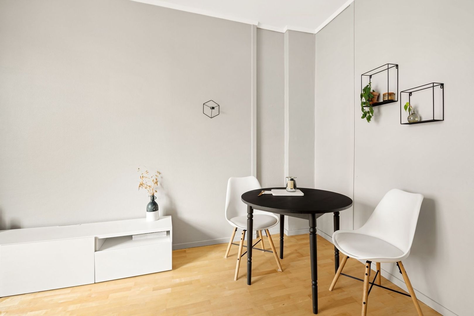 Ljust och avskalat vardagsrum med svart matbord och vita stolar